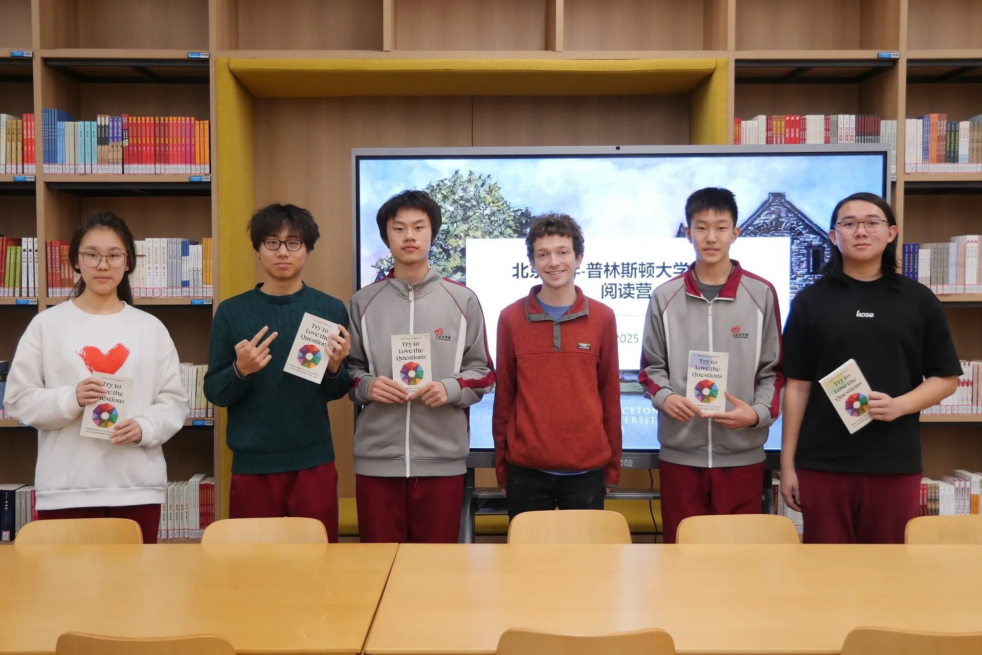 北京中学学生举着 "人如其读" 书本在「全球视野阅读营」背景前合影