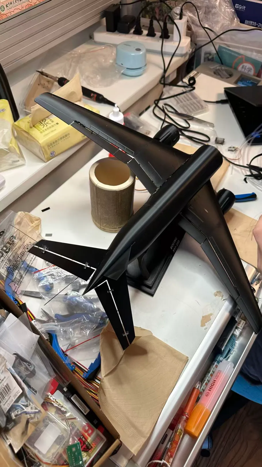 一台黑色的飞机模型摆在杂乱的工作台上